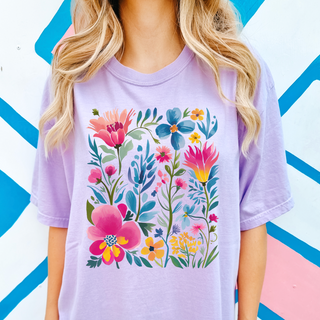 Person wearing a purple t-shirt with colorful floral design against a geometric patterned background