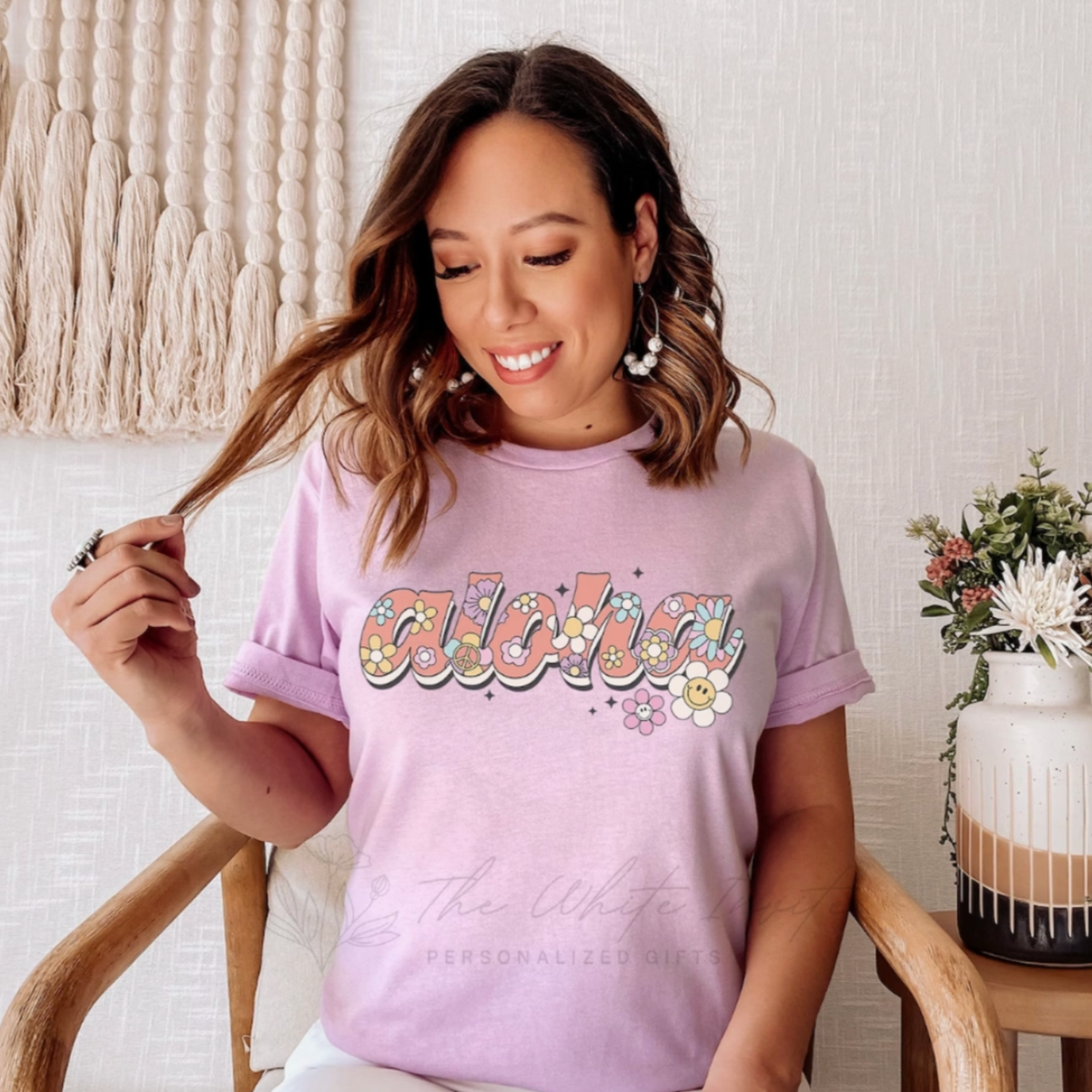 A women&#39;s graphic t-shirt with short sleeves, featuring a retro &quot;Aloha Summer&quot; design. The soft, comfortable tee comes in various colors like Heather Mauve and Heather Dust, and is available in sizes from Small to Extra Large.