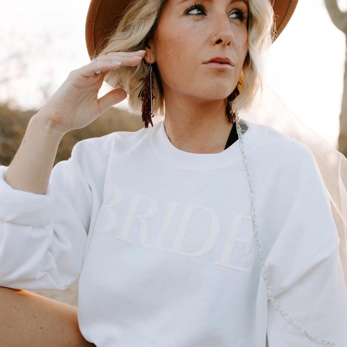 A women's crewneck sweatshirt with the word "Bride" elegantly embssed text on the front. This soft and comfortable white sweatshirt is perfect for the bride-to-be as she prepares for her big day. Available in unisex sizes Small to Extra Large, made from a preshrunk 50/50 cotton and polyester blend.