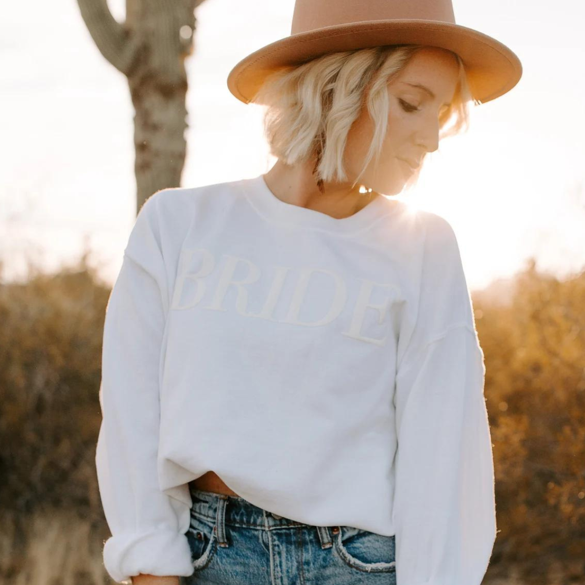 A women's crewneck sweatshirt with the word "Bride" elegantly embssed text on the front. This soft and comfortable white sweatshirt is perfect for the bride-to-be as she prepares for her big day. Available in unisex sizes Small to Extra Large, made from a preshrunk 50/50 cotton and polyester blend.