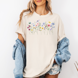Woman wearing a cream-colored t-shirt with floral design and denim jacket on a white background
