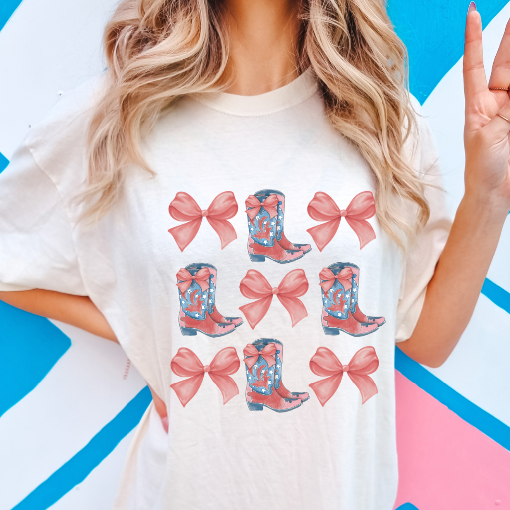 A women&#39;s graphic t-shirt with short sleeves, featuring Bow and Boot design. This soft, comfortable short sleeve tee from Comfort Colors is perfect for bachelorette parties. It is available in white with pink font or pink with white font, in sizes Small to 2XL.