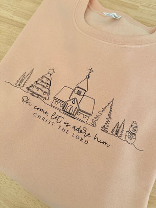 Beige sweatshirt with Christmas-themed design and text on a wooden surface