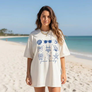 Woman wearing a white t-shirt dress with blue graphics on a beach