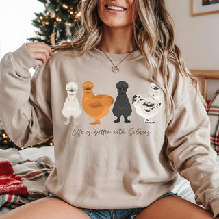 Woman wearing a beige sweatshirt with silkie chicken illustrations and text in a home setting.