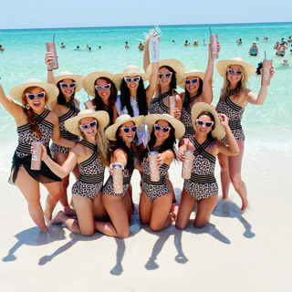 Group of women in matching outfits and hats on a beach