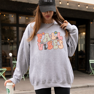 Person wearing a gray sweatshirt with 'Fairy Vibes' text, holding a Starbucks cup outdoors.