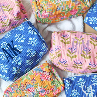 Colorful fabric pouches with monograms on a white surface