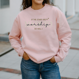 Person wearing a pink sweatshirt with text, standing outdoors.