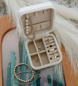 Open jewelry box with necklaces and rings on a decorative surface