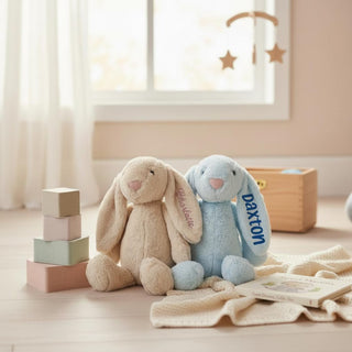 Two plush bunny toys named Charlotte and Daxton in a nursery setting with blocks and a blanket.