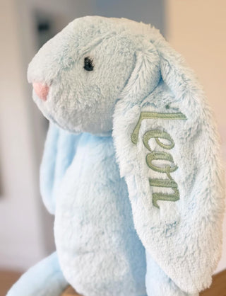 Blue plush bunny with 'Leon' embroidered on it against a blurred background