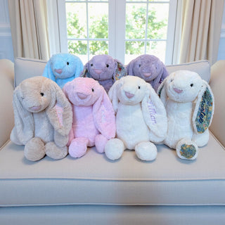 Set of colorful plush bunnies on a couch with a window in the background