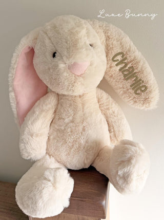 Plush bunny toy with 'Luxe Bunny' branding on a neutral background