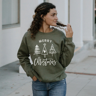 Woman wearing a green 'Merry Christmas' sweatshirt with tree designs outdoors.