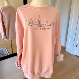 Pink sweatshirt with Christmas-themed design on a mannequin in a room.
