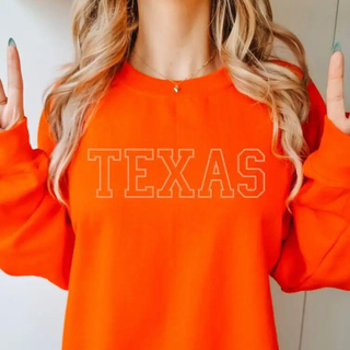 Person wearing an orange sweatshirt with 'TEXAS' printed on it, making a peace sign.
