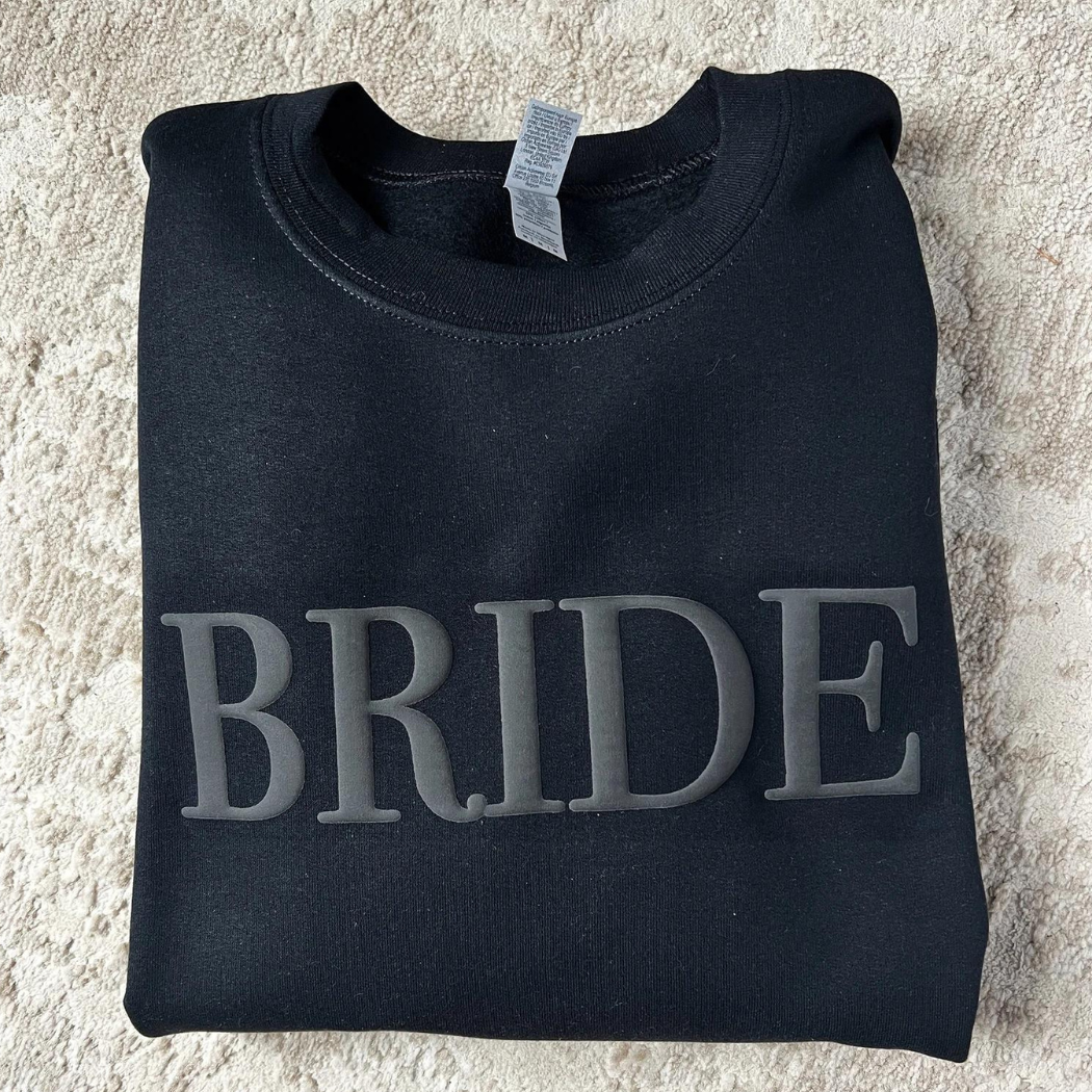 A women's crewneck sweatshirt with the word "Bride" elegantly embssed text on the front. This soft and comfortable black sweatshirt is perfect for the bride-to-be as she prepares for her big day. Available in unisex sizes Small to Extra Large, made from a preshrunk 50/50 cotton and polyester blend.