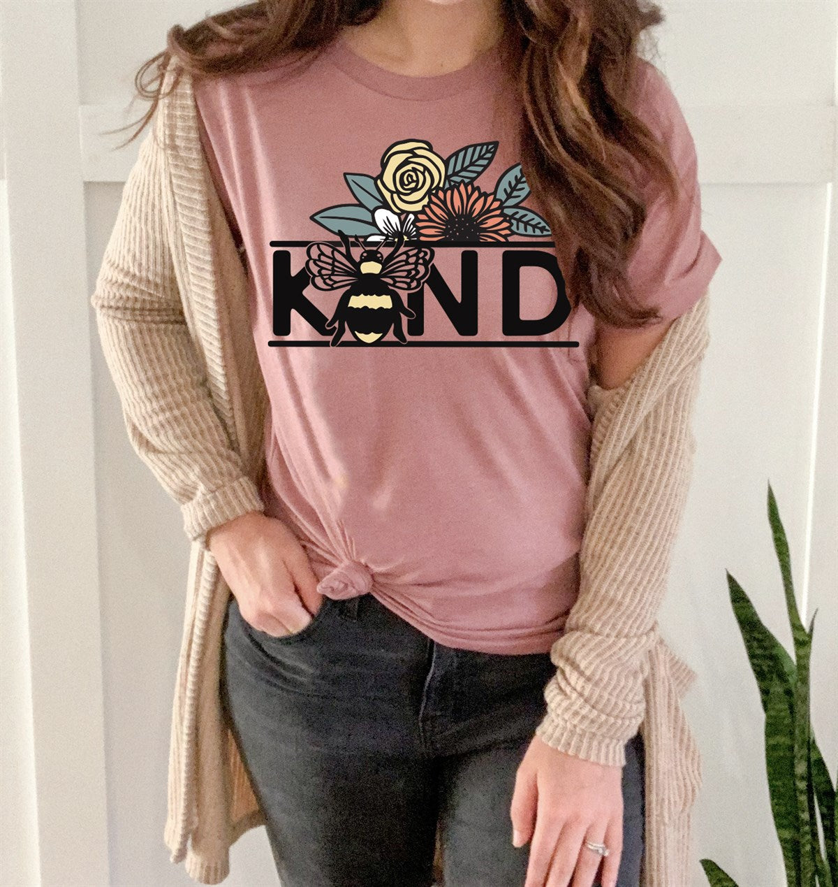  A women's graphic t-shirt with short sleeves, featuring the phrase "Bee Kind" alongside a cute bee illustration. This soft and comfortable Bella Canvas short sleeve tee is perfect for spreading positivity and comes in colors like Heather Mauve, Heather Dust, Heather Peach, Heather Navy, Heather Green, Heather Robin, Heather Clay, and Heather Red, available in sizes Small to Extra Large.