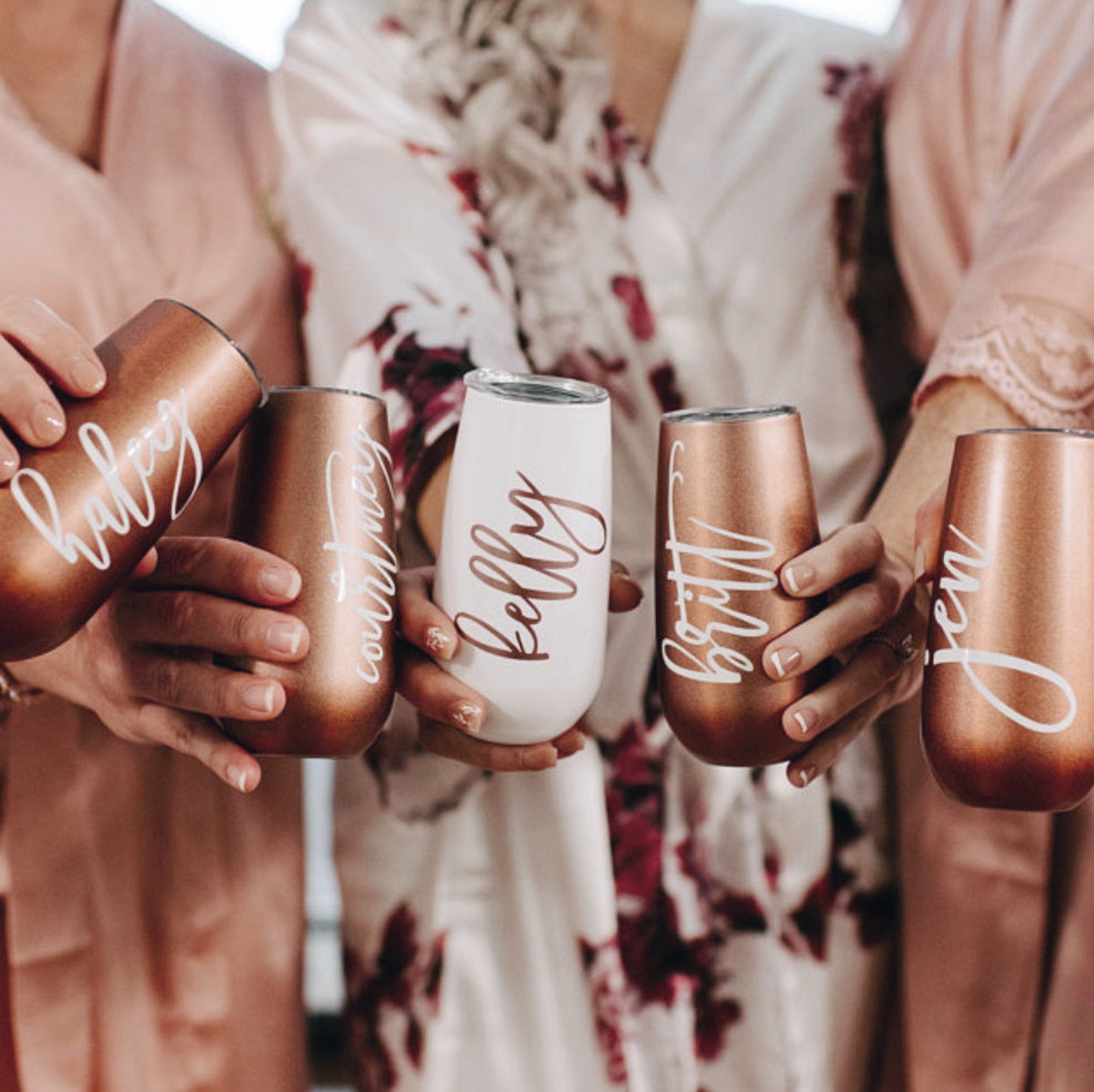 Personalized rose gold and white champagne flutes with lids, perfect for bridesmaids, weddings, or gifts. These elegant wine glass tumblers can be customized with a name, making them a unique and thoughtful present. Designed to keep drinks cold for up to 24 hours, they combine practicality with stylish design, ideal for celebrating special occasions.